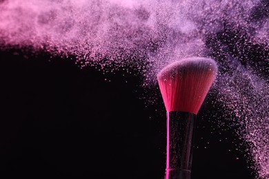Photo of Makeup brush with pink eye shadow on black background, closeup