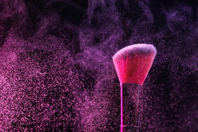 Photo of Makeup brush with pink eye shadow on black background, closeup