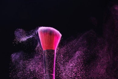 Photo of Makeup brush with color eye shadow on black background, closeup