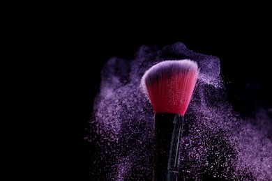 Photo of Makeup brush with purple eye shadow on black background, closeup. Space for text