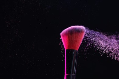 Photo of Makeup brush with color eye shadow on black background, closeup. Space for text