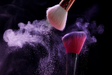 Photo of Makeup brushes with purple eye shadow on black background, closeup. Space for text