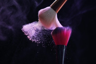 Photo of Makeup brushes with purple eye shadow on black background, closeup. Space for text