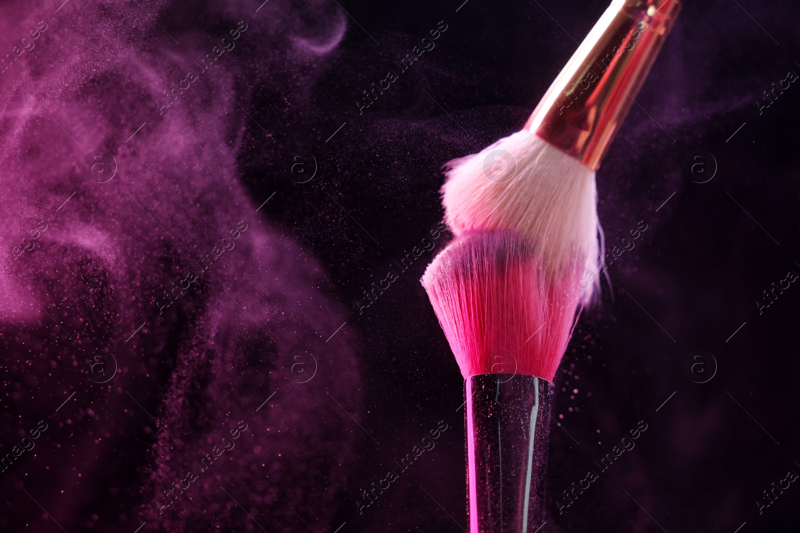 Makeup brushes with pink eye shadow in neon lights on black background, closeup. Space for text Photo of Makeup brushes with pink eye shadow in neon lights on black background, closeup. Space for text