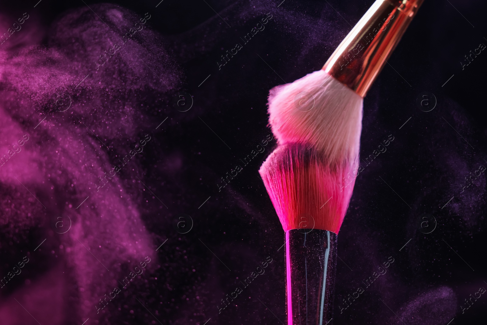 Makeup brushes with pink eye shadow in neon lights on black background, closeup. Space for text Photo of Makeup brushes with pink eye shadow in neon lights on black background, closeup. Space for text