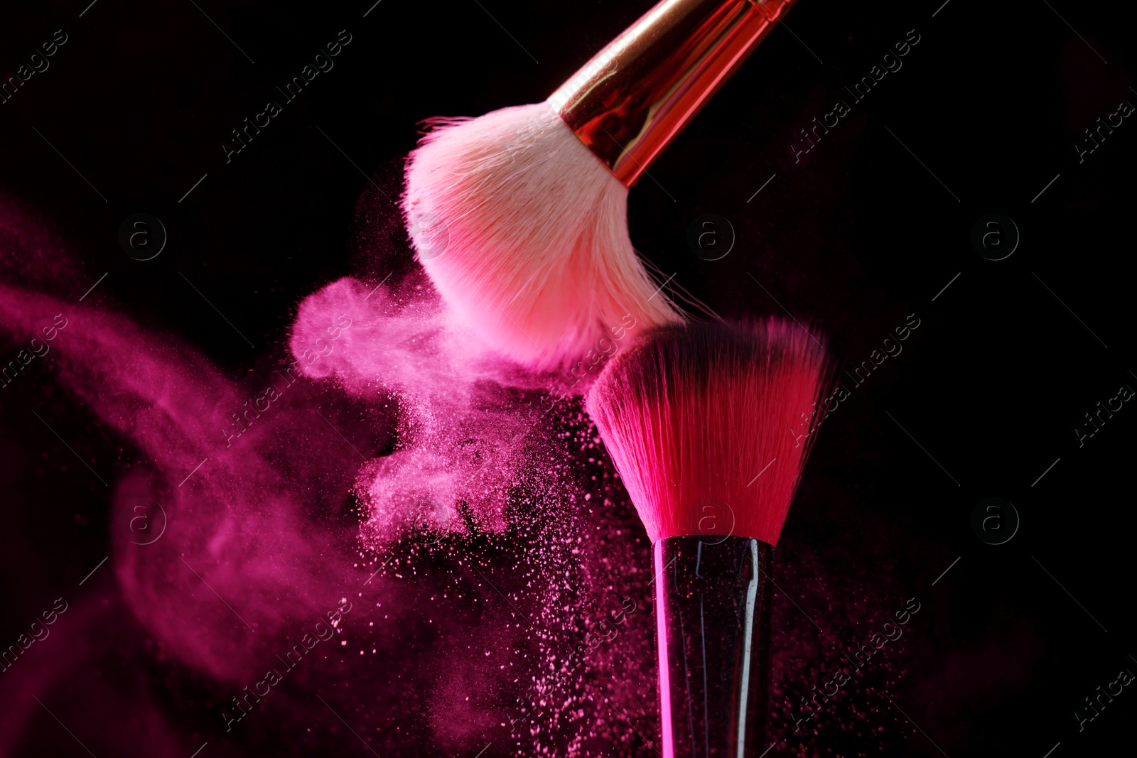 Makeup brushes with pink eye shadow on black background, closeup Photo of Makeup brushes with pink eye shadow on black background, closeup