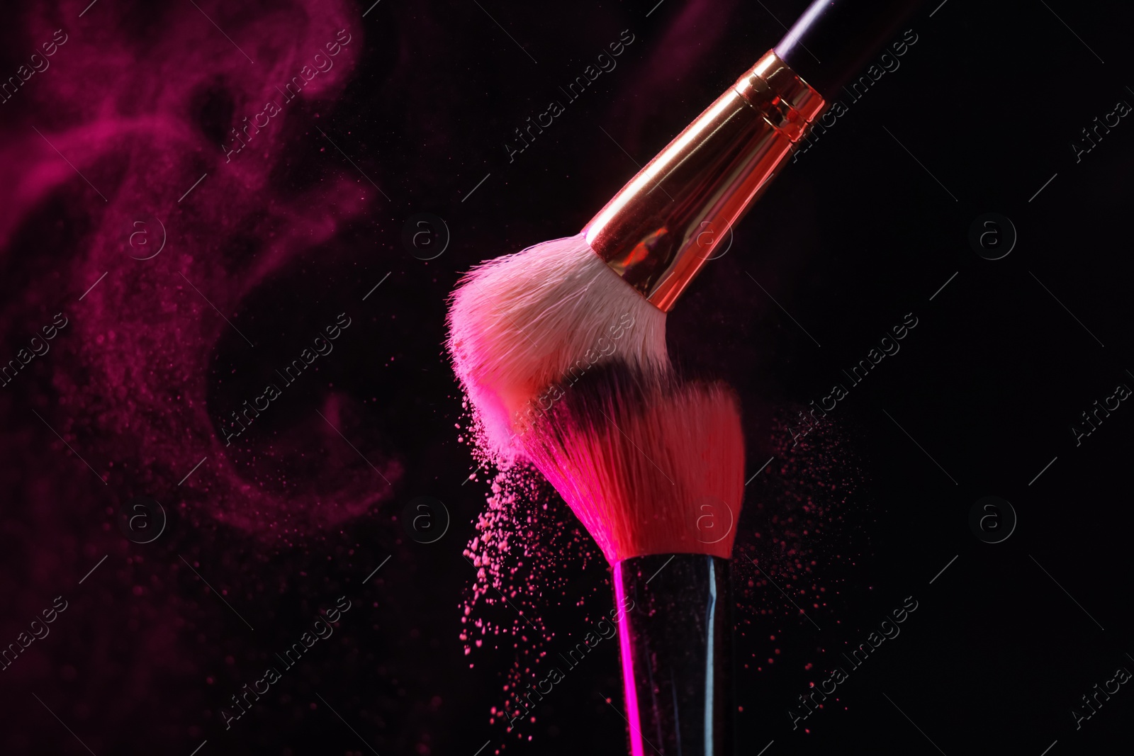 Makeup brushes with pink eye shadow on black background, closeup Photo of Makeup brushes with pink eye shadow on black background, closeup