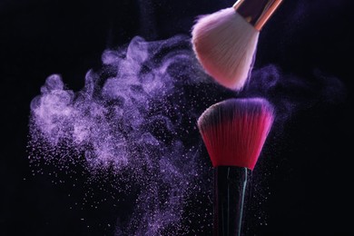 Photo of Makeup brushes with purple eye shadow on black background, closeup. Space for text