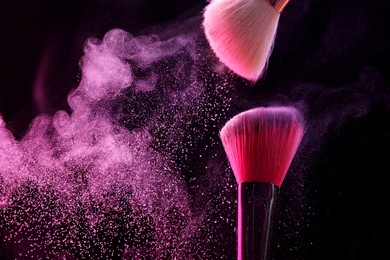 Photo of Makeup brushes with pink eye shadow on black background, closeup. Space for text