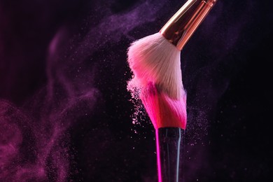 Photo of Makeup brushes with color eye shadow on black background, closeup. Space for text