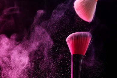 Photo of Makeup brushes with pink eye shadow on black background, closeup. Space for text