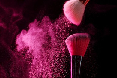 Photo of Makeup brushes with pink eye shadow on black background, closeup. Space for text