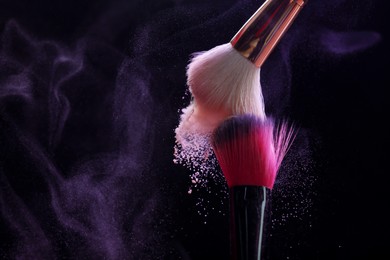 Photo of Makeup brushes with purple eye shadow on black background, closeup. Space for text