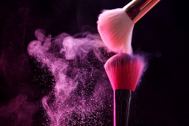 Photo of Makeup brushes with pink eye shadow on black background, closeup. Space for text