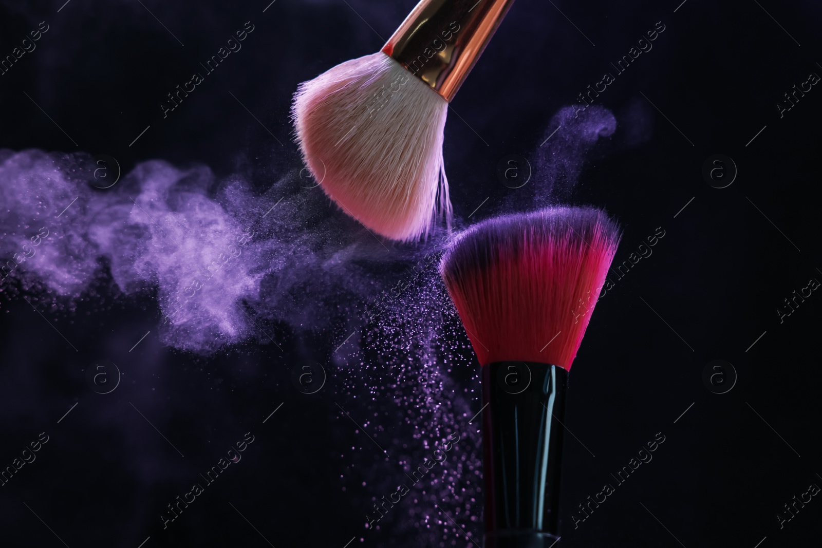 Makeup brushes with purple eye shadow in neon lights on black background, closeup Photo of Makeup brushes with purple eye shadow in neon lights on black background, closeup