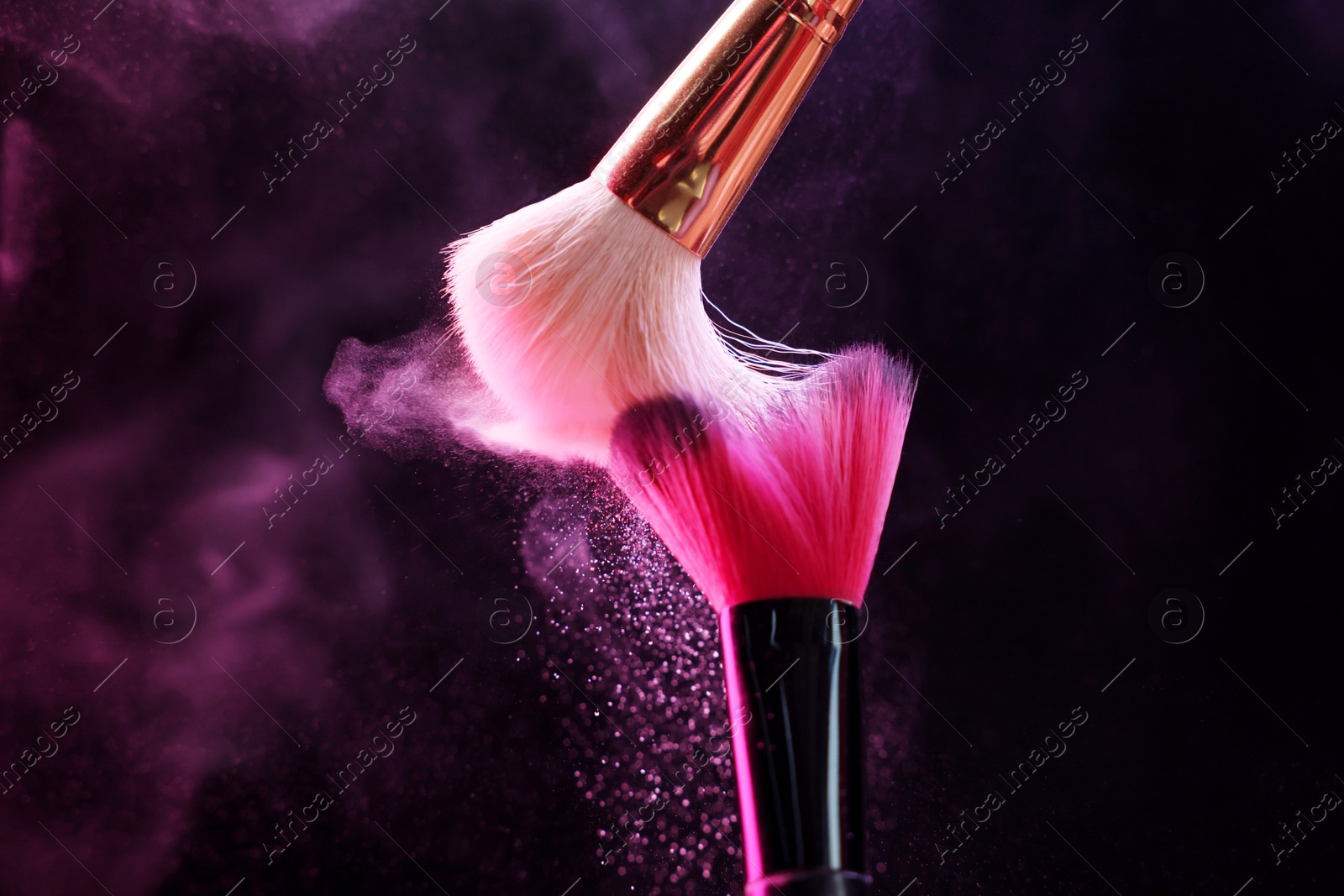 Makeup brushes with colorful eye shadows in neon lights on black background, closeup Photo of Makeup brushes with colorful eye shadows in neon lights on black background, closeup