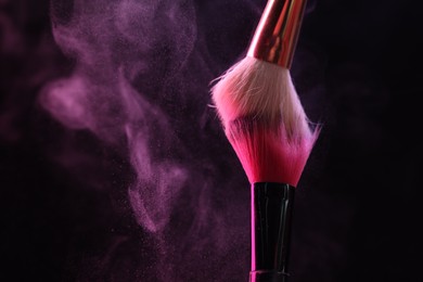Photo of Makeup brushes with pink eye shadow on black background, closeup. Space for text