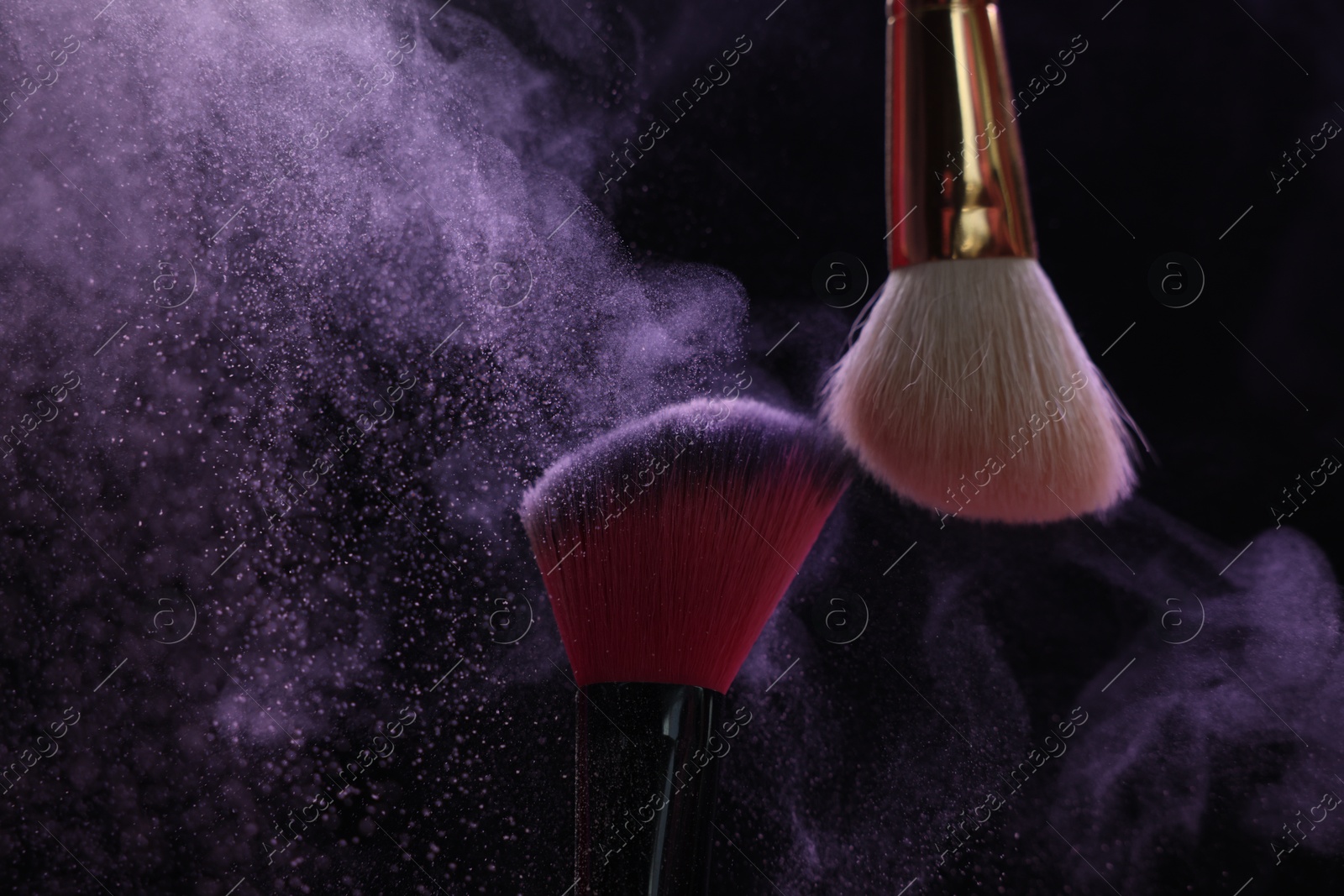 Makeup brushes with purple eye shadow on black background, closeup Photo of Makeup brushes with purple eye shadow on black background, closeup