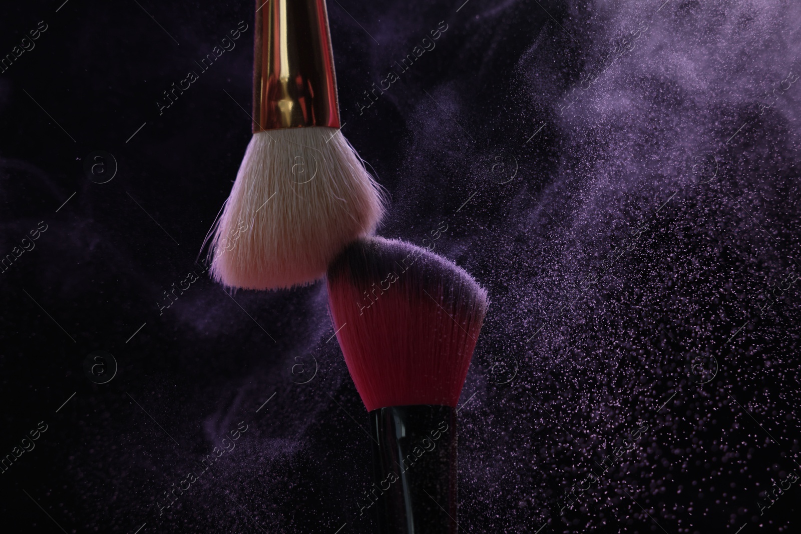 Makeup brushes with purple eye shadow on black background, closeup Photo of Makeup brushes with purple eye shadow on black background, closeup