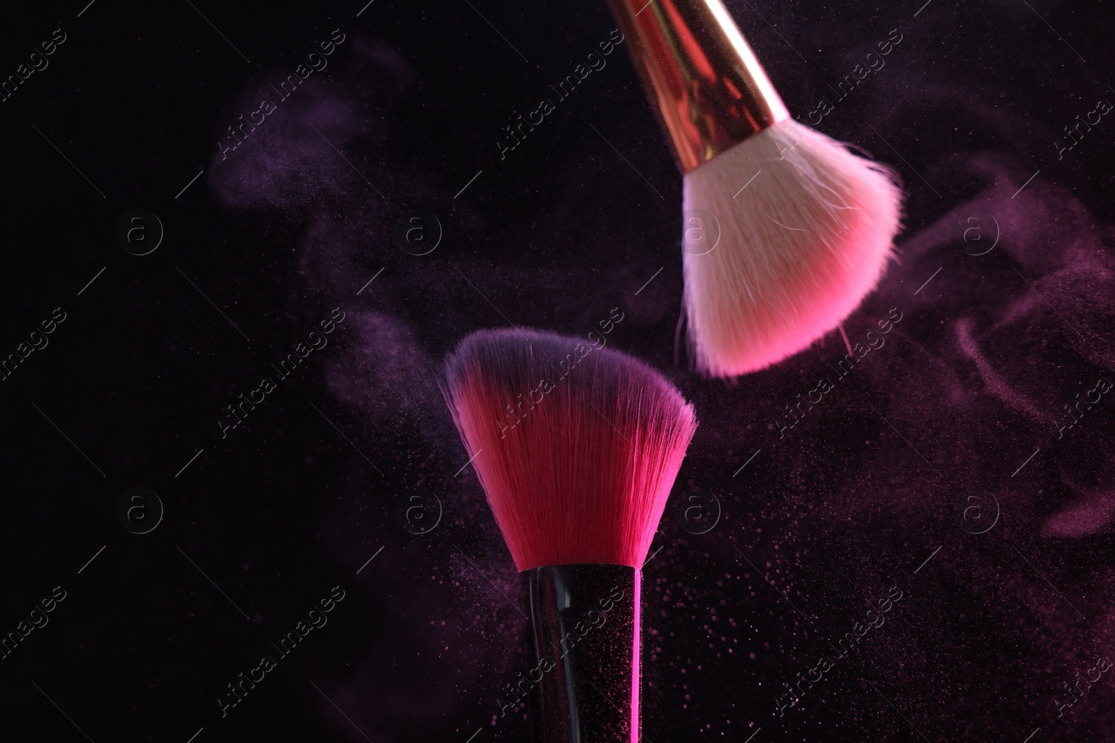Makeup brushes with pink eye shadow on black background, closeup Photo of Makeup brushes with pink eye shadow on black background, closeup
