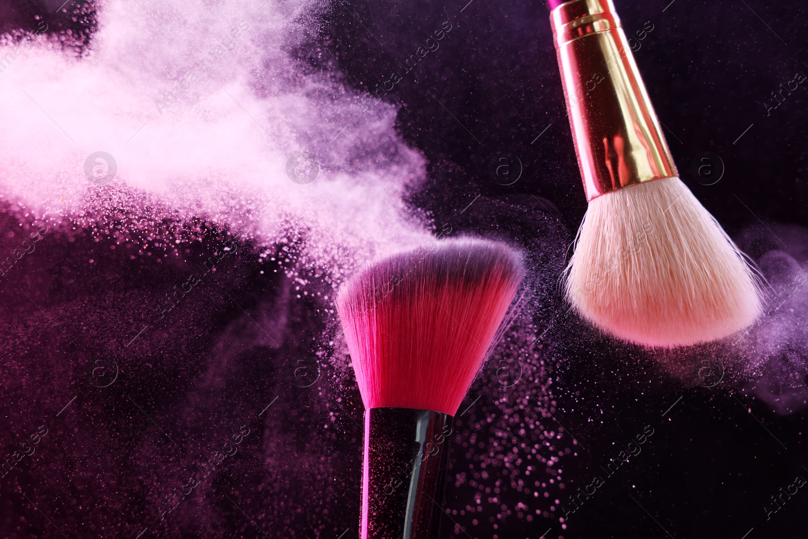 Makeup brushes with pink eye shadow on black background, closeup Photo of Makeup brushes with pink eye shadow on black background, closeup
