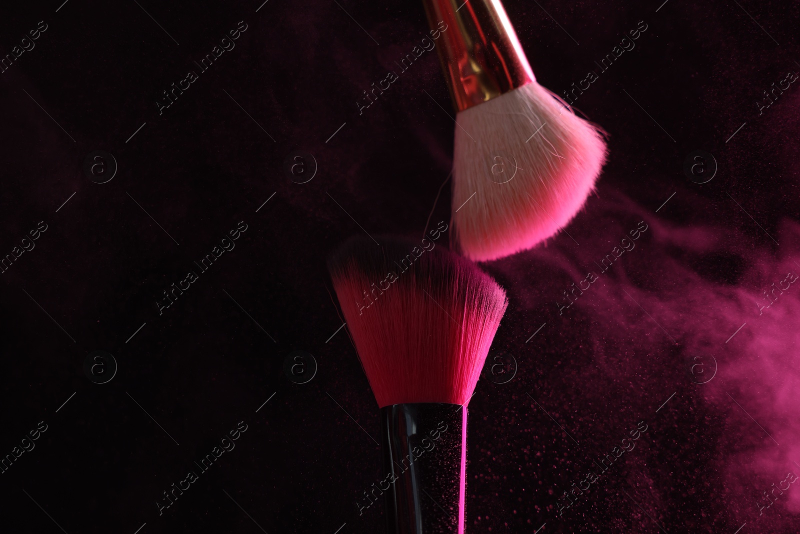 Makeup brushes with pink eye shadow on black background, closeup Photo of Makeup brushes with pink eye shadow on black background, closeup