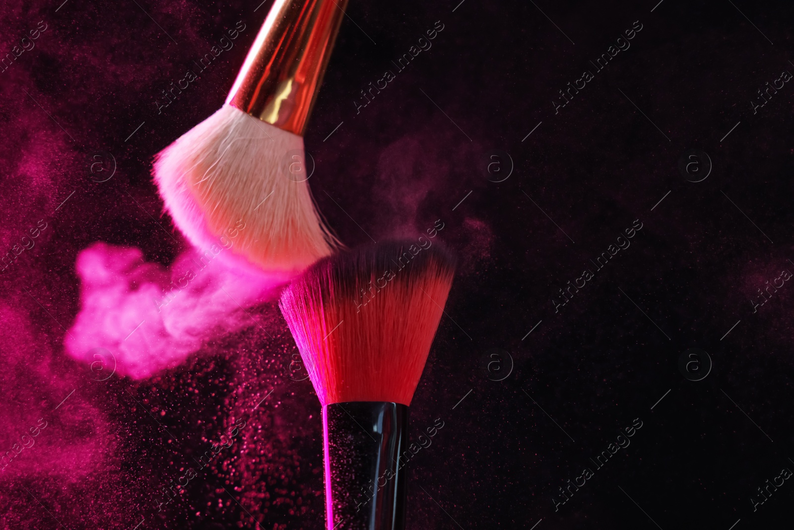 Makeup brushes with pink eye shadow on black background, closeup Photo of Makeup brushes with pink eye shadow on black background, closeup