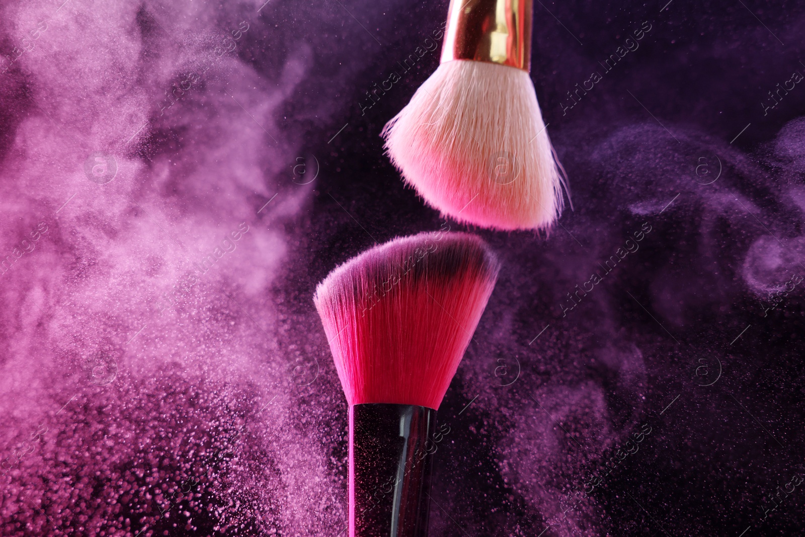 Makeup brushes with colorful eye shadows in neon lights on black background, closeup Photo of Makeup brushes with colorful eye shadows in neon lights on black background, closeup