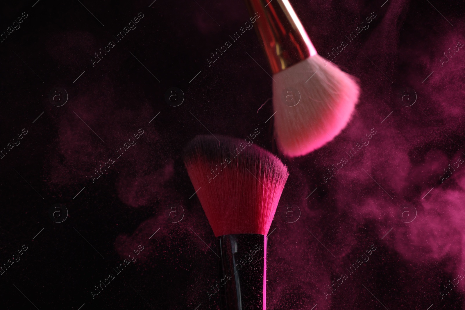Makeup brushes with pink eye shadow on black background, closeup Photo of Makeup brushes with pink eye shadow on black background, closeup