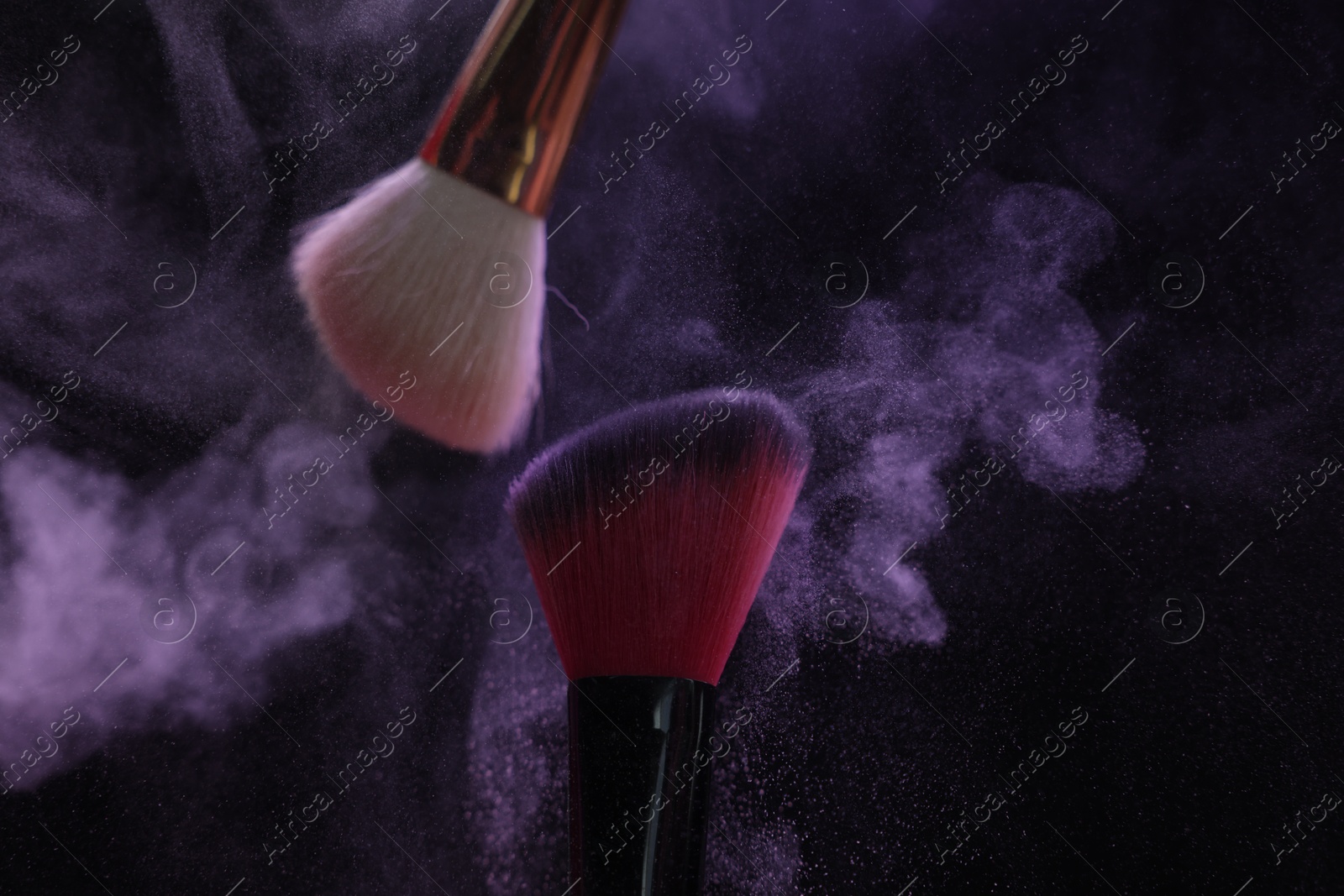 Makeup brushes with purple eye shadow on black background, closeup Photo of Makeup brushes with purple eye shadow on black background, closeup