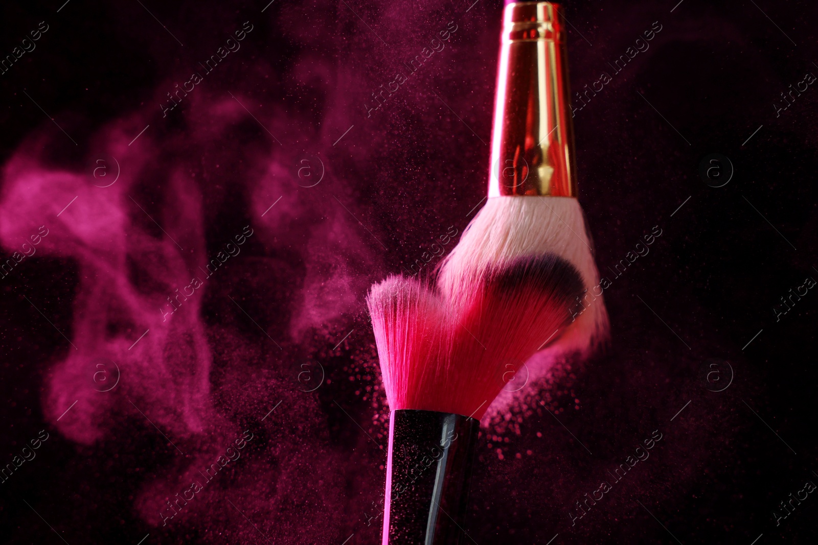 Makeup brushes with pink eye shadow on black background, closeup Photo of Makeup brushes with pink eye shadow on black background, closeup