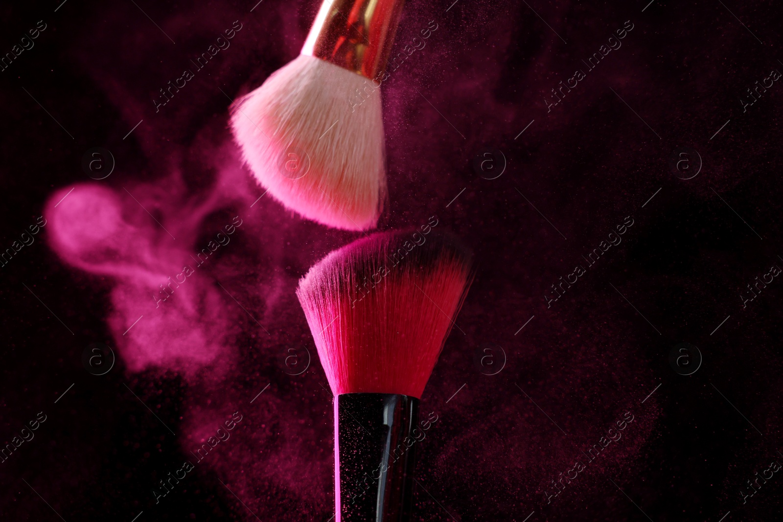Makeup brushes with pink eye shadow on black background, closeup Photo of Makeup brushes with pink eye shadow on black background, closeup