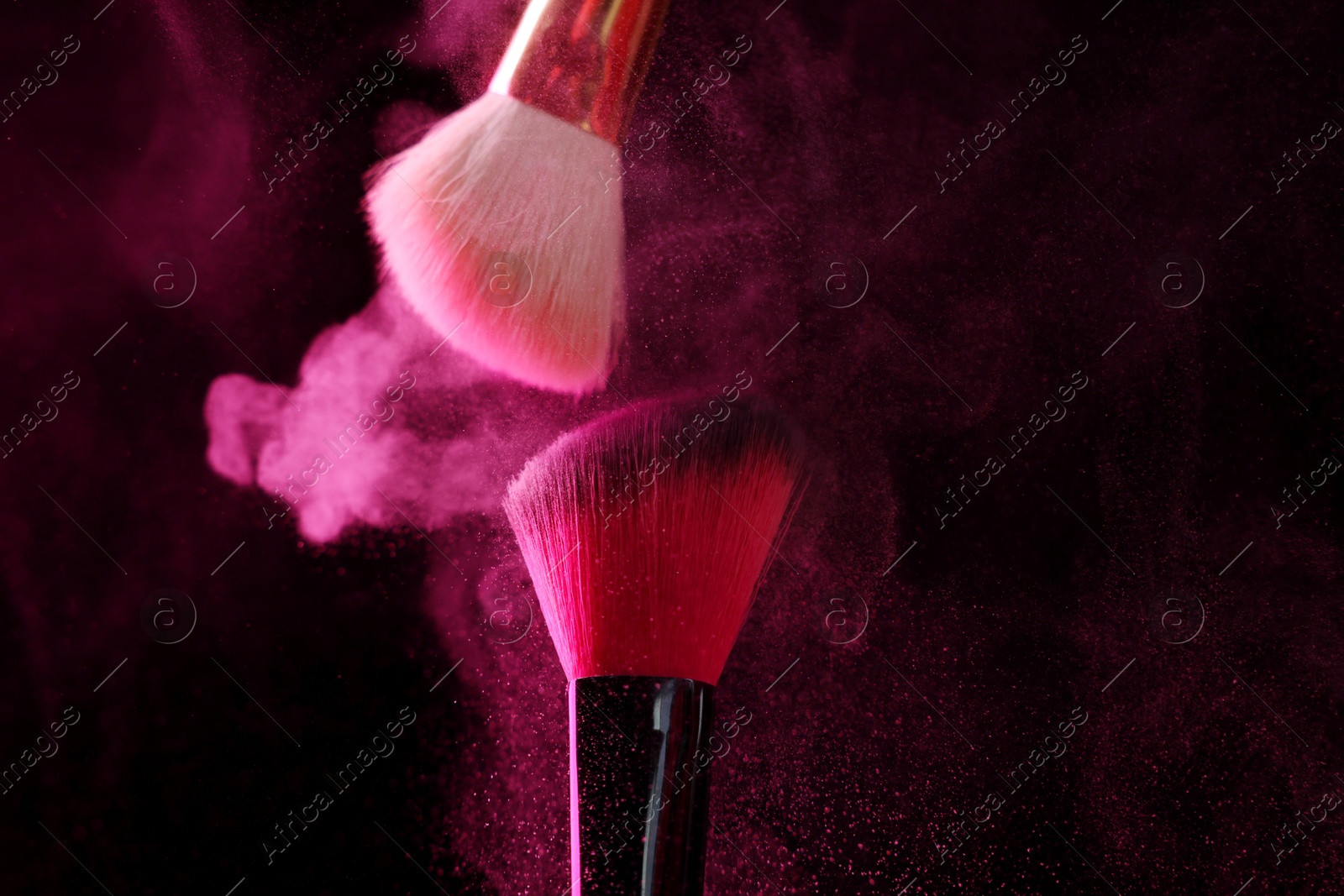Makeup brushes with pink eye shadow on black background, closeup Photo of Makeup brushes with pink eye shadow on black background, closeup