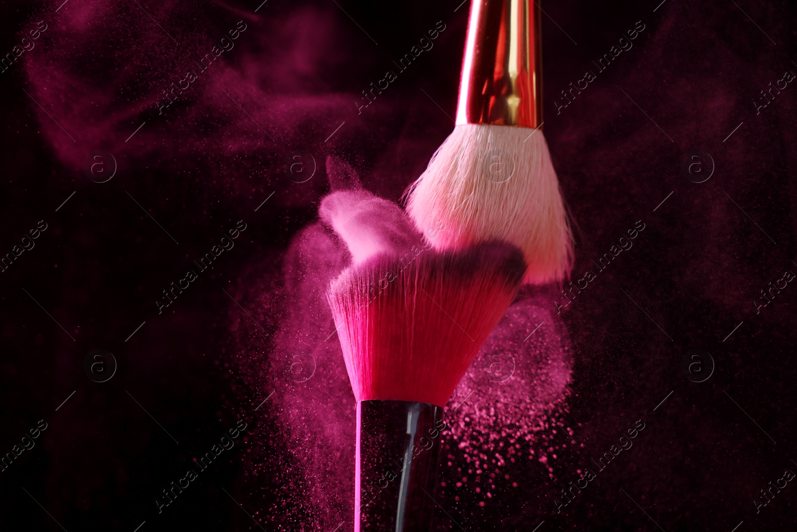 Makeup brushes with pink eye shadow on black background, closeup Photo of Makeup brushes with pink eye shadow on black background, closeup
