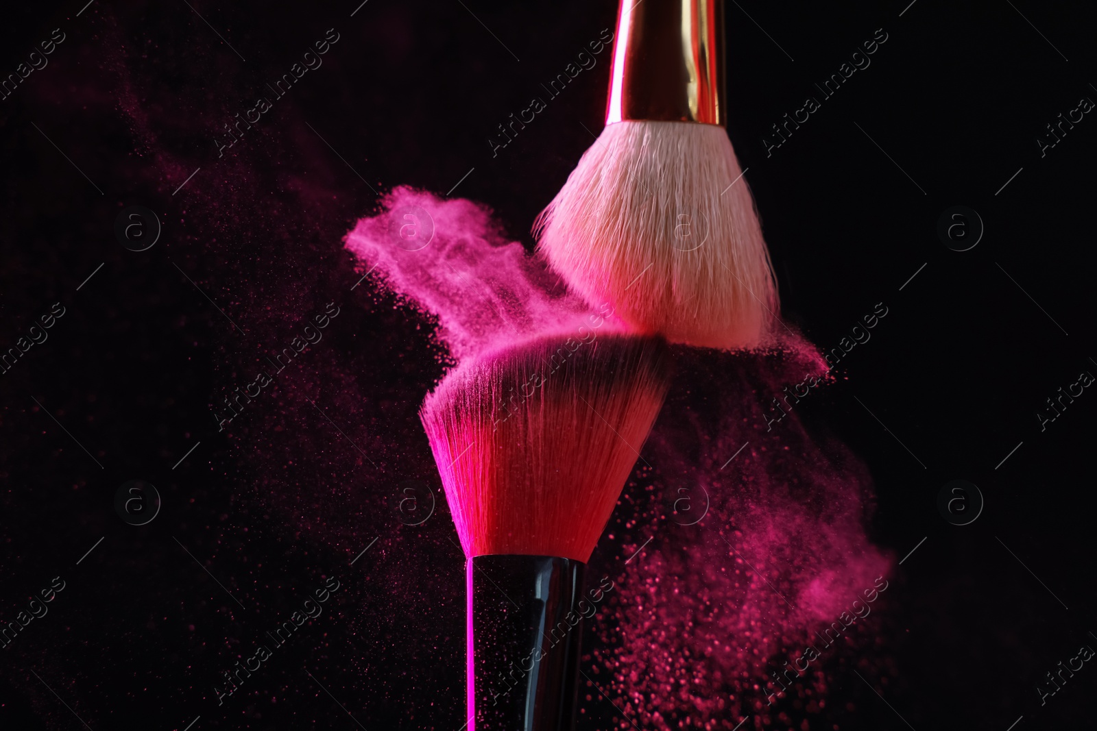 Makeup brushes with pink eye shadow on black background, closeup Photo of Makeup brushes with pink eye shadow on black background, closeup
