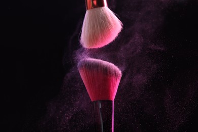 Photo of Makeup brushes with color eye shadow on black background, closeup