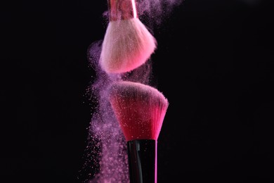Photo of Makeup brushes with color eye shadow on black background, closeup