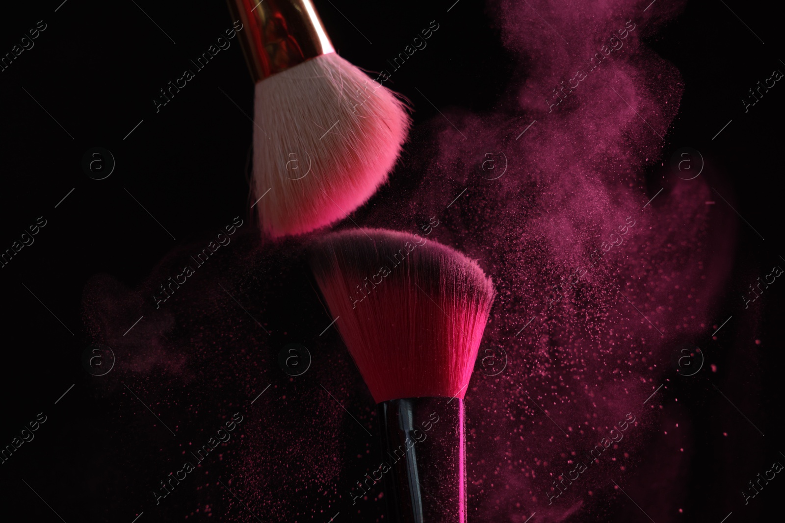 Makeup brushes with pink eye shadow on black background, closeup Photo of Makeup brushes with pink eye shadow on black background, closeup