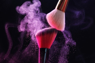 Photo of Makeup brushes with colorful eye shadows on black background, closeup