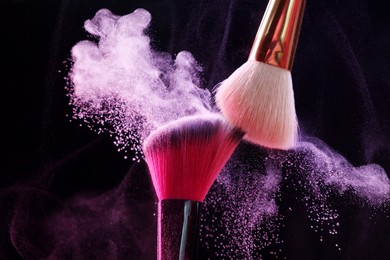 Photo of Makeup brushes with colorful eye shadows on black background, closeup