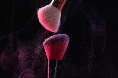 Photo of Makeup brushes with colorful eye shadows on black background, closeup