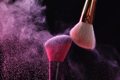Photo of Makeup brushes with colorful eye shadows on black background, closeup