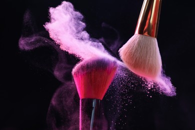 Photo of Makeup brushes with colorful eye shadows on black background, closeup