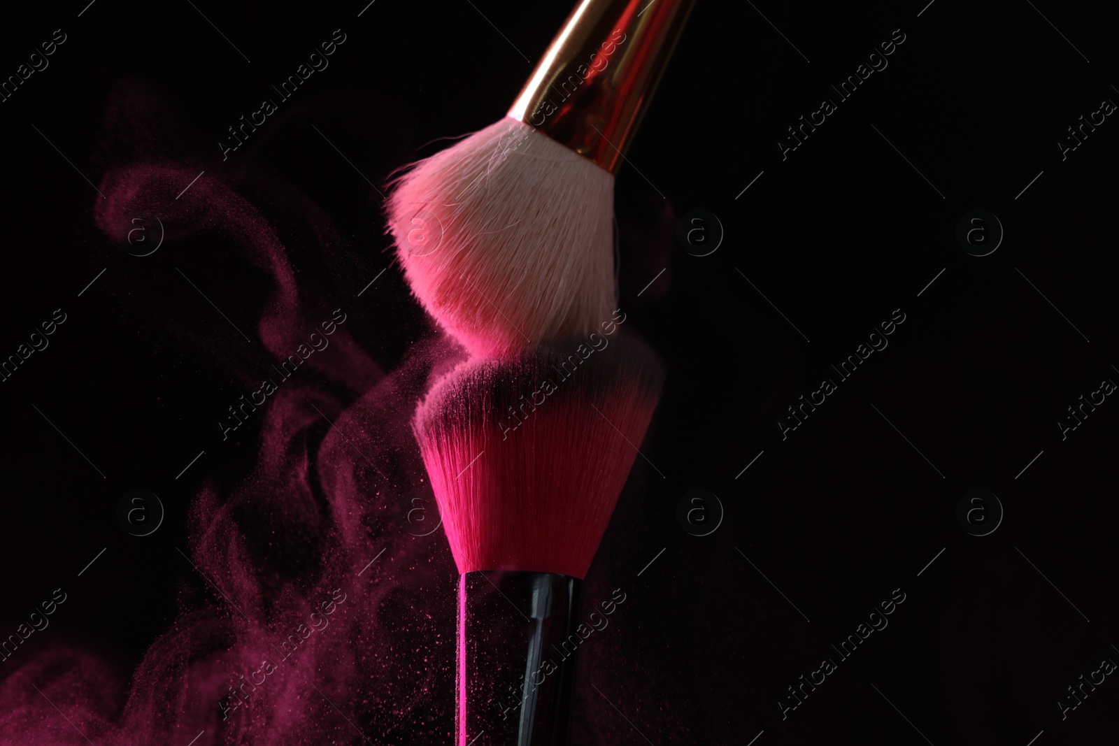 Makeup brushes with pink eye shadow on black background, closeup Photo of Makeup brushes with pink eye shadow on black background, closeup