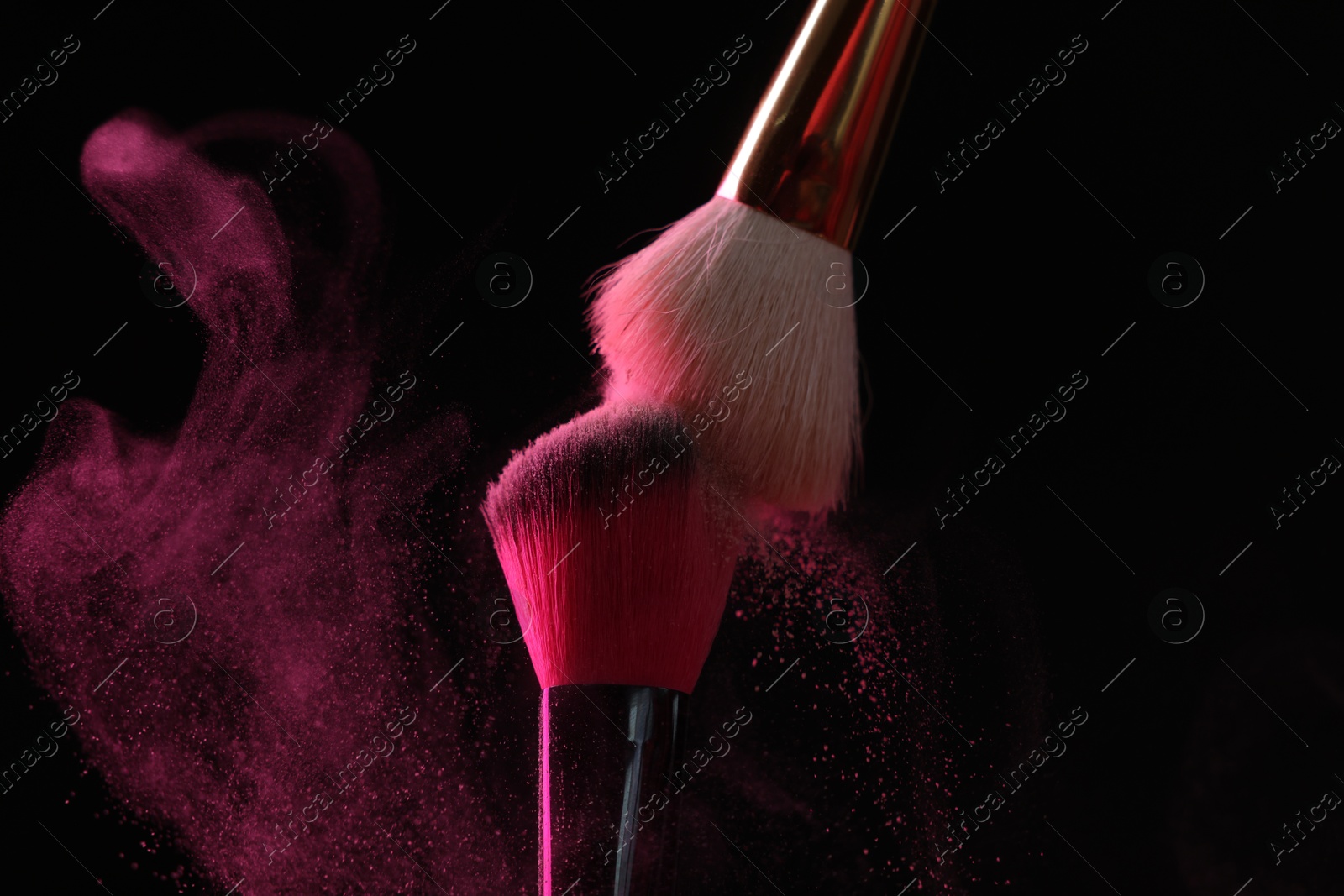 Makeup brushes with pink eye shadow on black background, closeup Photo of Makeup brushes with pink eye shadow on black background, closeup