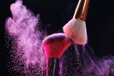 Photo of Makeup brushes with colorful eye shadows on black background, closeup