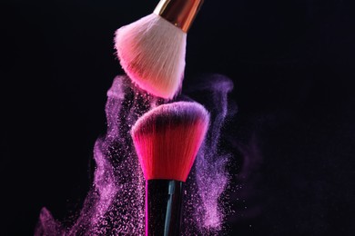 Photo of Makeup brushes with colorful eye shadows on black background, closeup