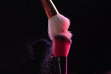 Photo of Makeup brushes with colorful eye shadows on black background, closeup
