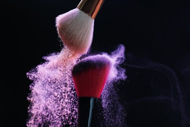 Photo of Makeup brushes with colorful eye shadows on black background, closeup