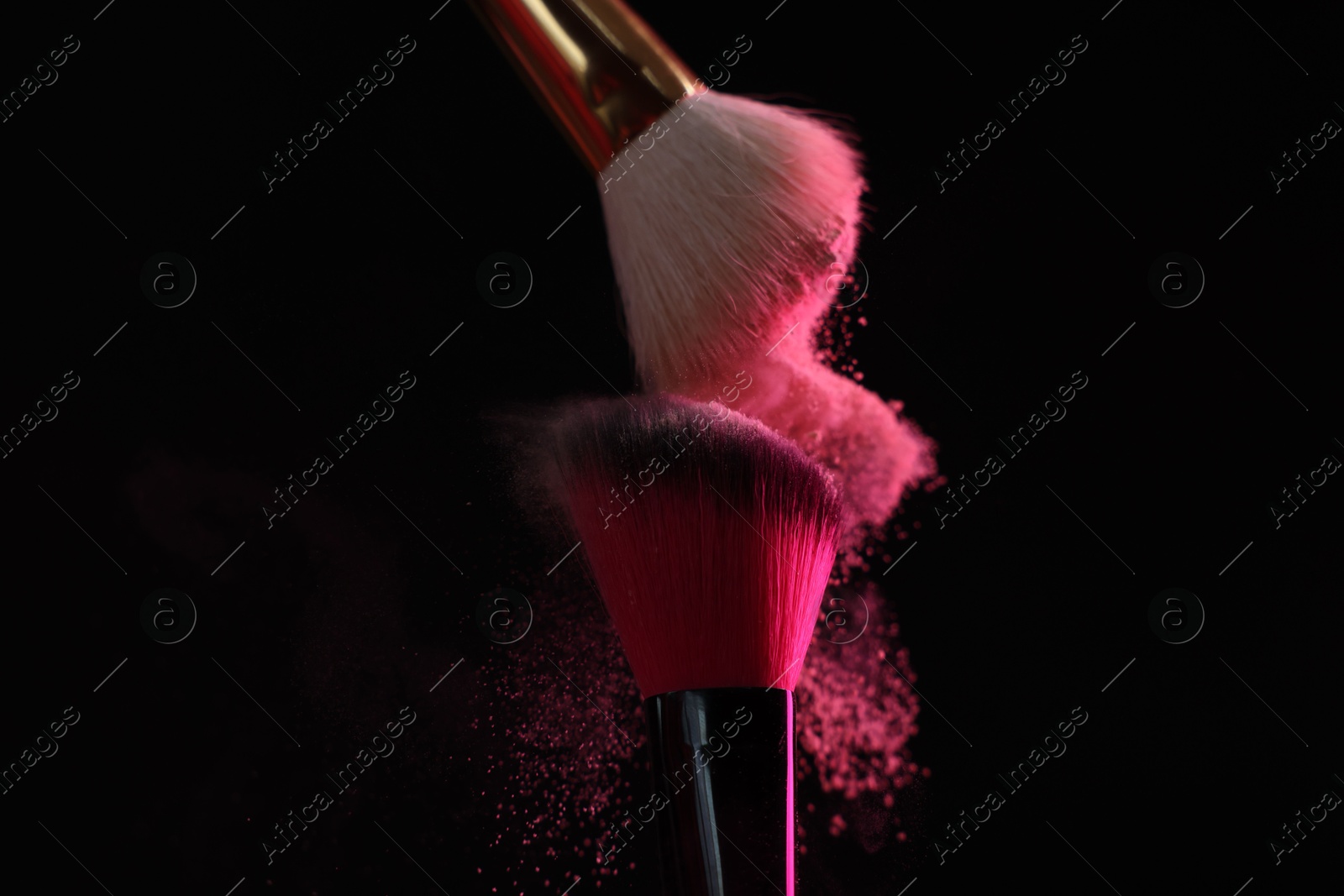 Makeup brushes with pink eye shadow on black background, closeup Photo of Makeup brushes with pink eye shadow on black background, closeup